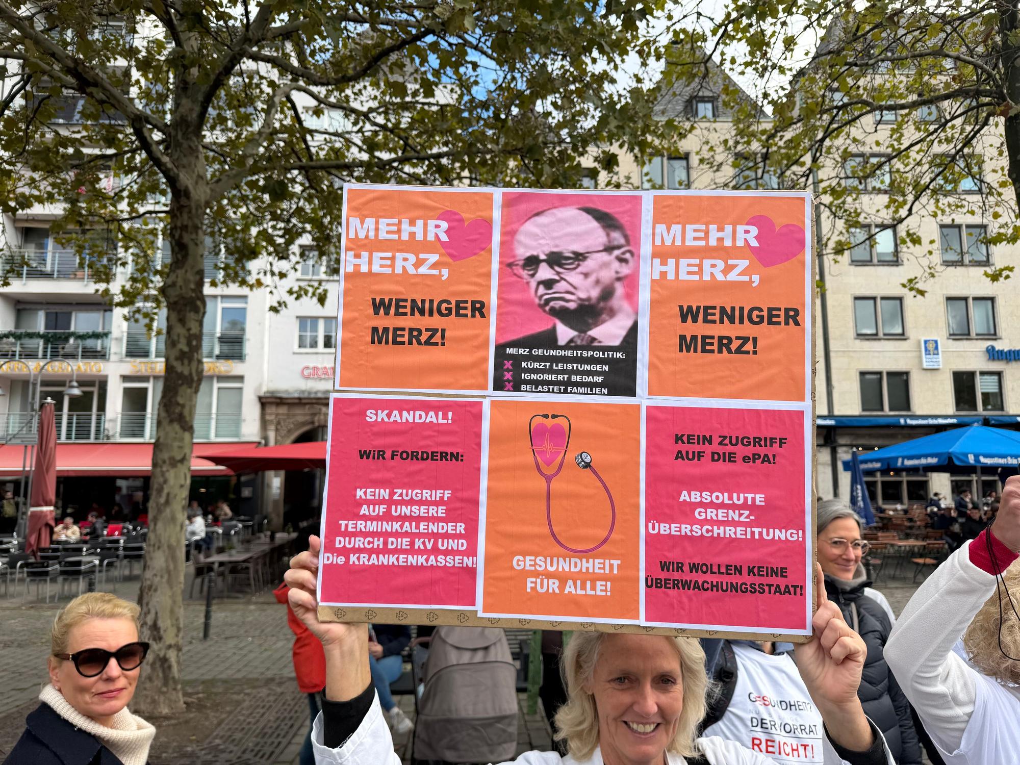 Eine Teilnehmende hält ein Plakat hoch mit der Forderung „Mehr Herz, weniger Merz“.