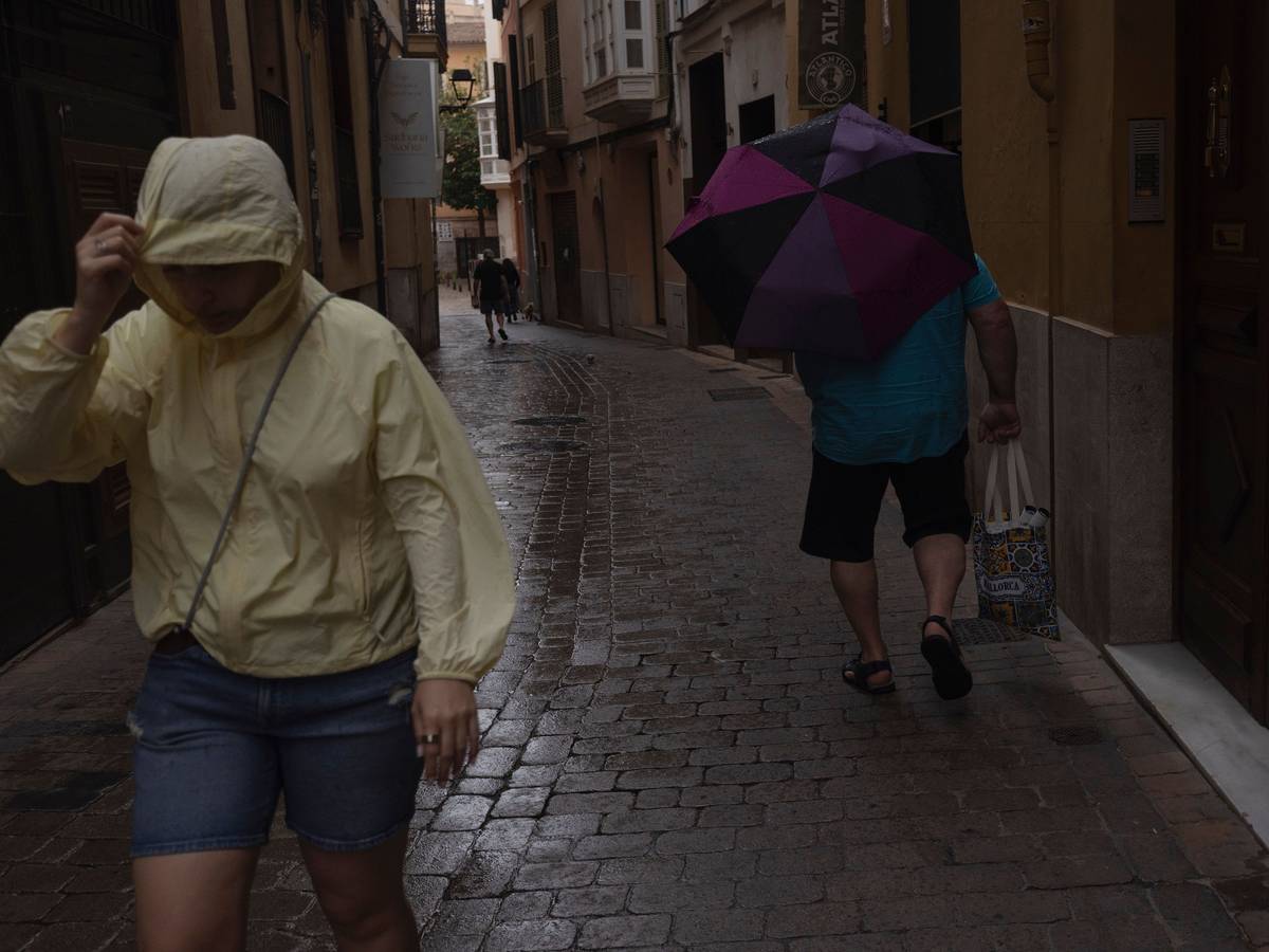 Menschen gehen im Regen durch die Innenstadt von Palma. Der Sturm „Adam“ zieht über die Insel hinweg, und für die Bevölkerung wurde eine rote Warnstufe ausgerufen.