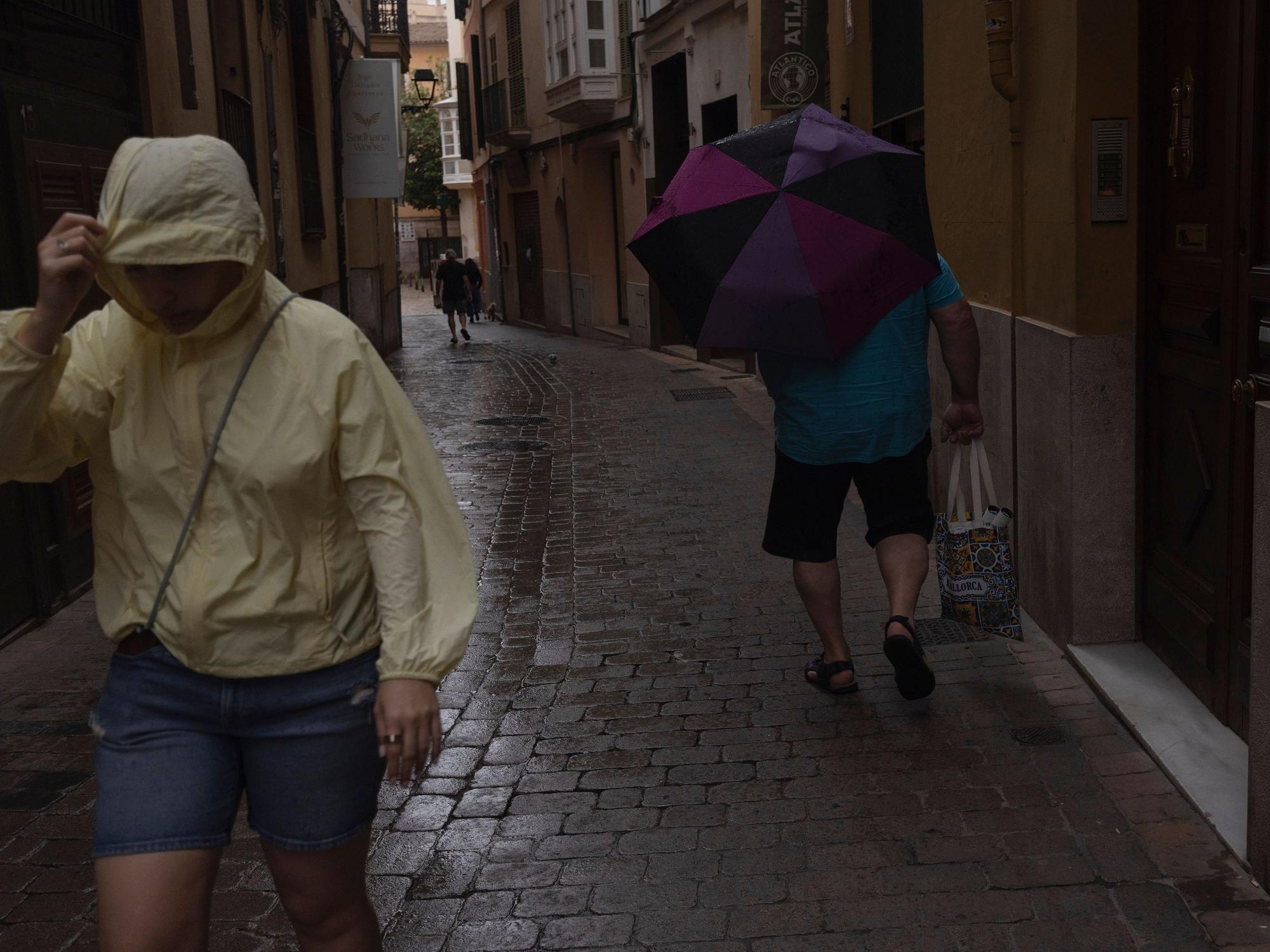 Menschen gehen im Regen durch die Innenstadt von Palma. Der Sturm „Adam“ zieht über die Insel hinweg, und für die Bevölkerung wurde eine rote Warnstufe ausgerufen.