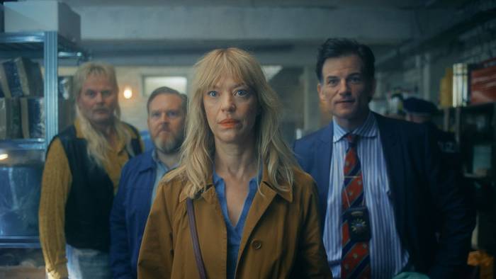 Wandas Mutter Carlotta (Heike Makatsch), deren Bruder Rüdiger (Devid Striesow, links) und Ehemann Dedo (Axel Stein, zweiter von links) sind von Wandas Unschuld überzeugt. Kommissar Schmidt (Torben Liebrecht) dagegen stellt sich quer. (Bild: Apple TV)