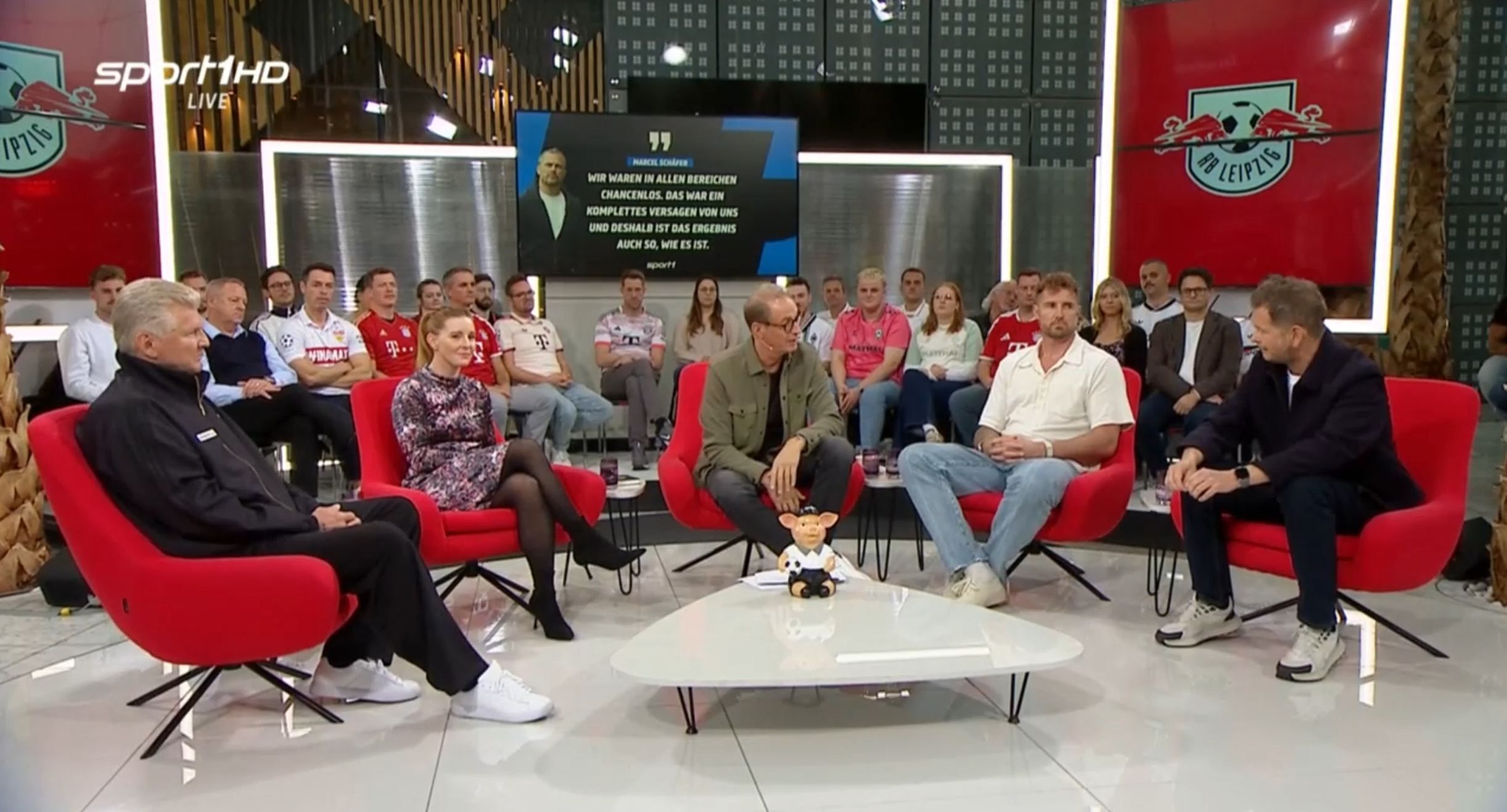 Die Doppelpass-Gäste und Moderator Florian König sitzen auf roten Sesseln.