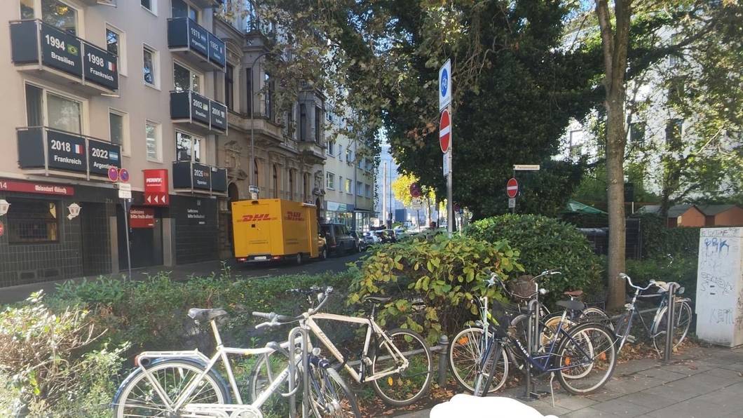 Ein Pfeil zeigt auf eine Stelle zwischen geparkten Fahrrädern.