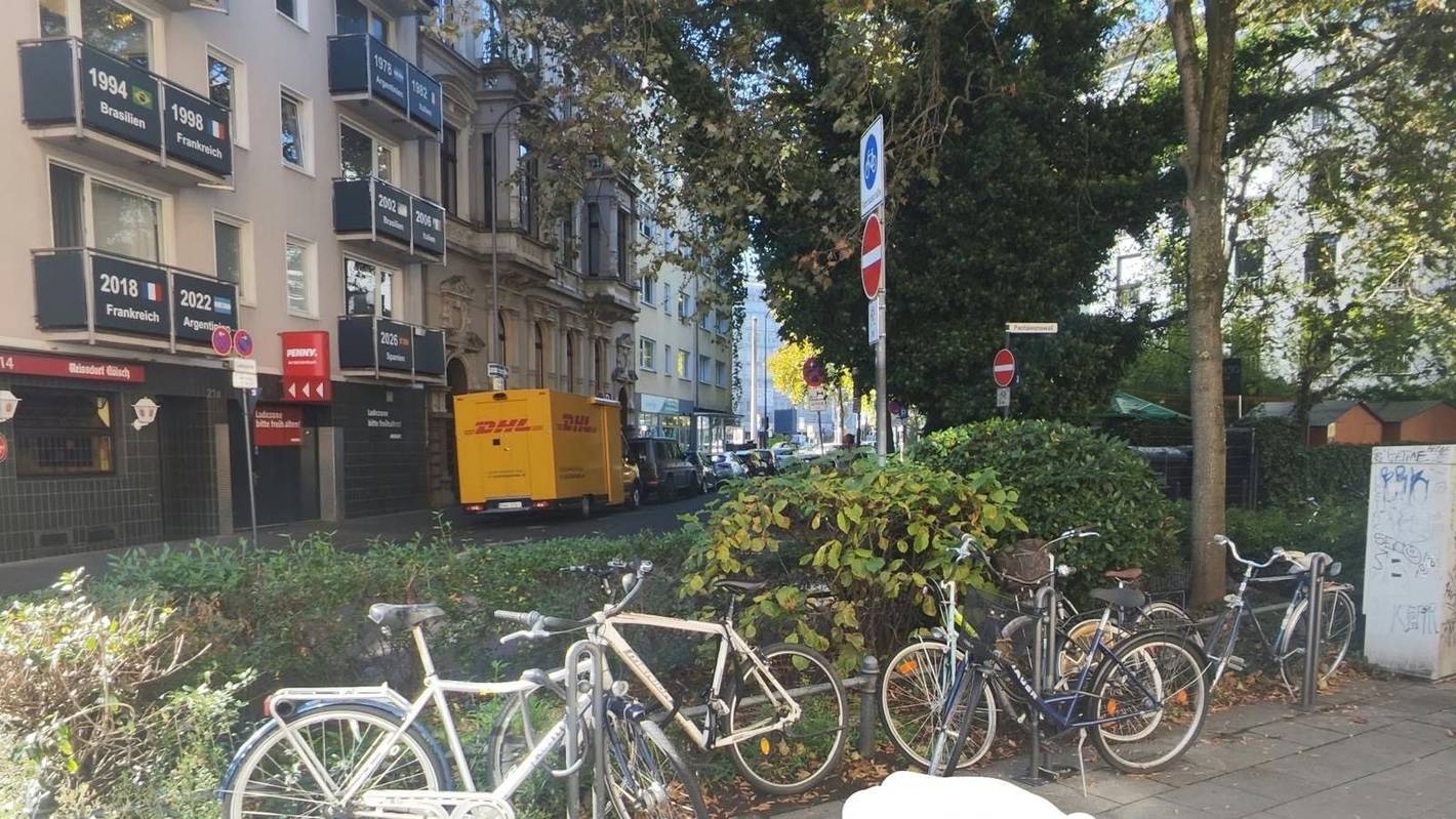Ein Pfeil zeigt auf eine Stelle zwischen geparkten Fahrrädern.