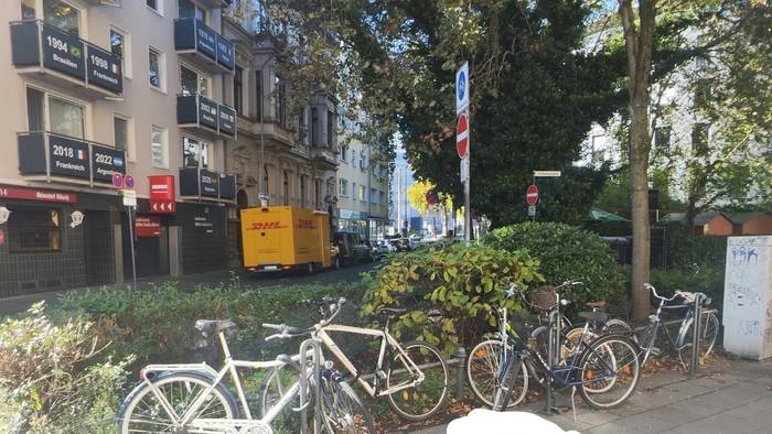 Ein Pfeil zeigt auf eine Stelle zwischen geparkten Fahrrädern.