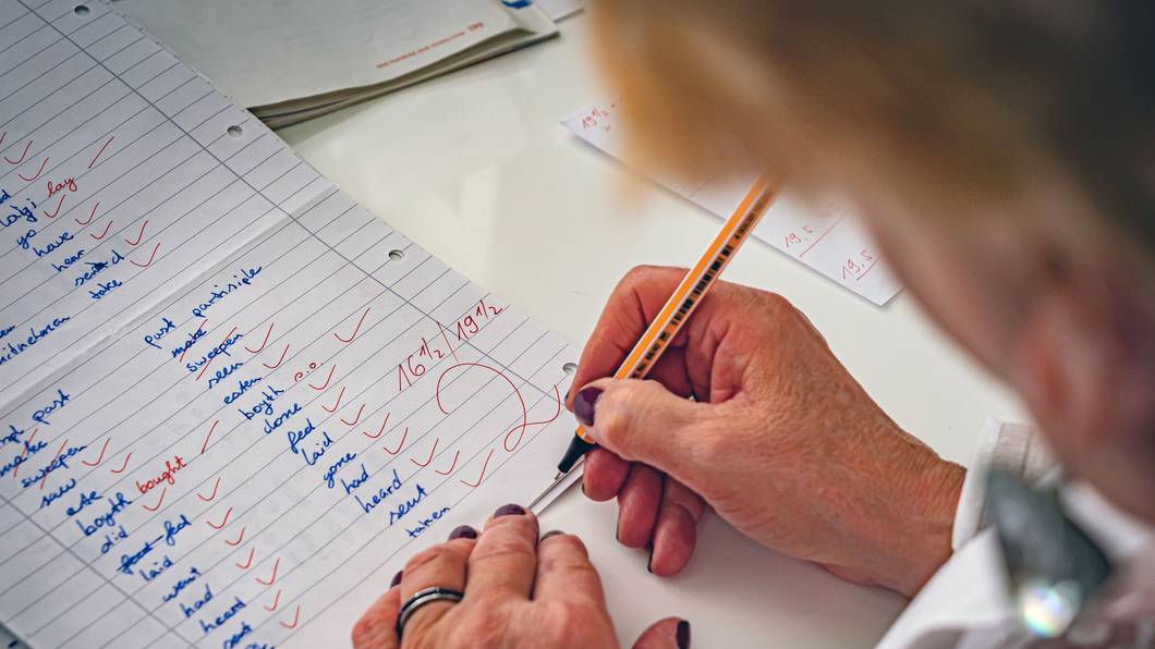 Eine Lehrerin korrigiert Klassenarbeiten. (Symbolfoto)