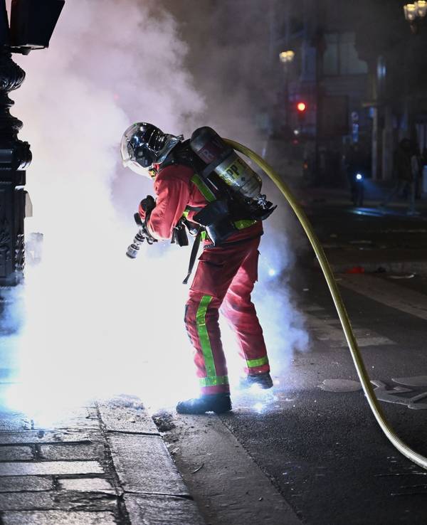 Ein Feuerwehrmann löscht einen Brand während Zusammenstößen zwischen Demonstranten und der Polizei.