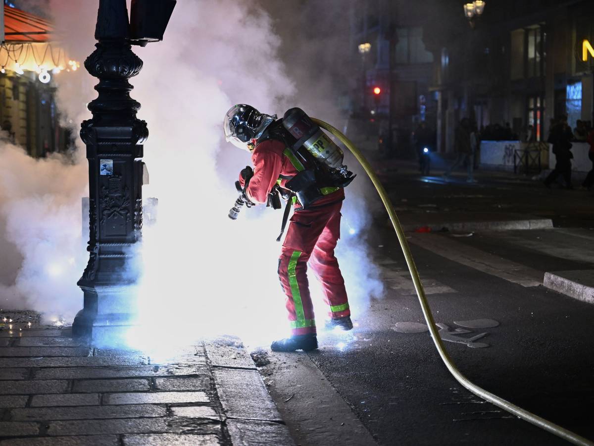 Ein Feuerwehrmann löscht einen Brand während Zusammenstößen zwischen Demonstranten und der Polizei.