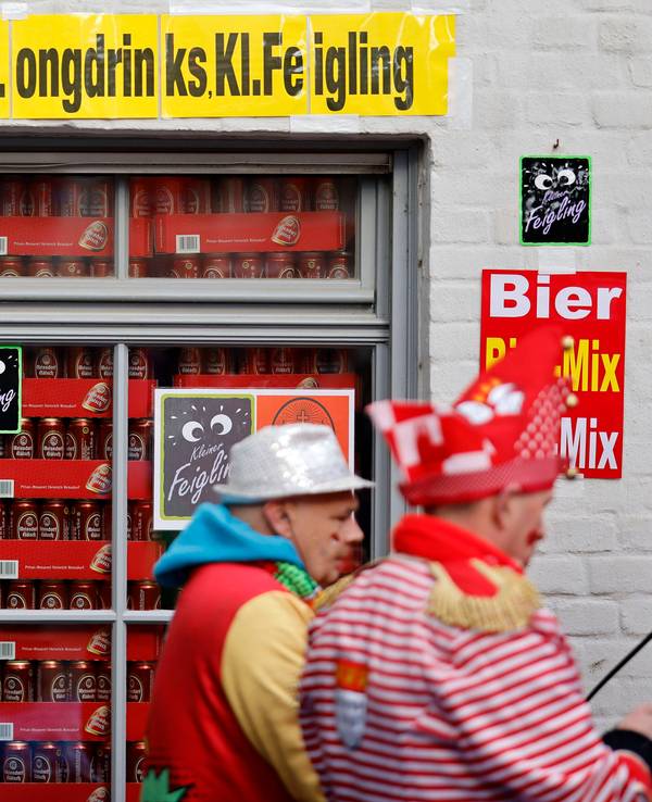 Verkleidete Jecken vor einem Schaufenster voller Bierdosen