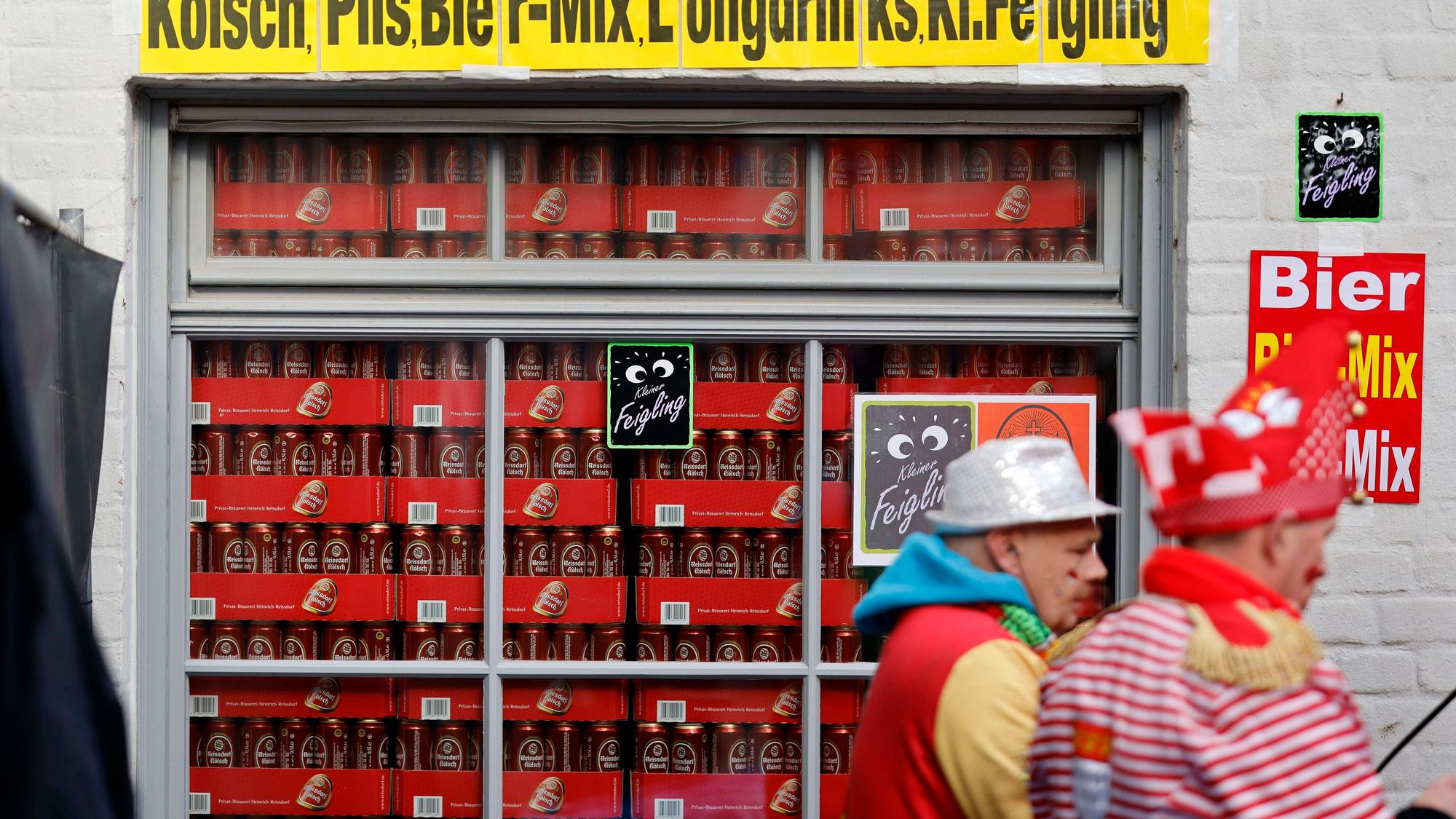 Verkleidete Jecken vor einem Schaufenster voller Bierdosen