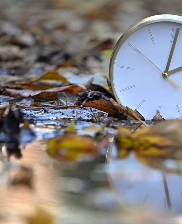 Eine Uhr spiegelt sich im blätterbedeckten Wasser. Mit Beginn der Winterzeit werden in Deutschland und den meisten anderen Ländern Europas am Sonntagmorgen (25. Oktober) die Uhren von 3.00 Uhr auf 2.00 Uhr zurückgestellt.