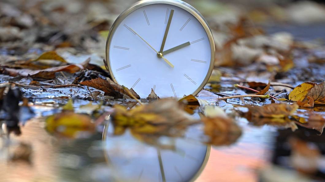 Eine Uhr spiegelt sich im blätterbedeckten Wasser. Mit Beginn der Winterzeit werden in Deutschland und den meisten anderen Ländern Europas am Sonntagmorgen (25. Oktober) die Uhren von 3.00 Uhr auf 2.00 Uhr zurückgestellt.
