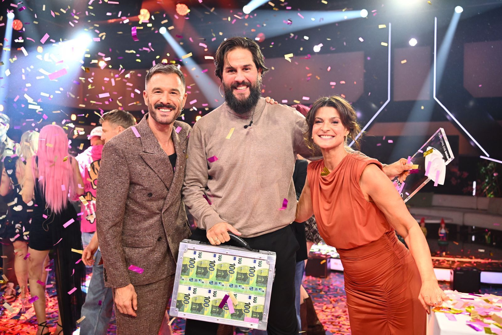 Maurice Dziwak (Mitte) bekommt von Jochen Schropp und Marlene Lufen den Pokal und 100.000 Euro überreicht. (Bild: Joyn/Willi Weber)