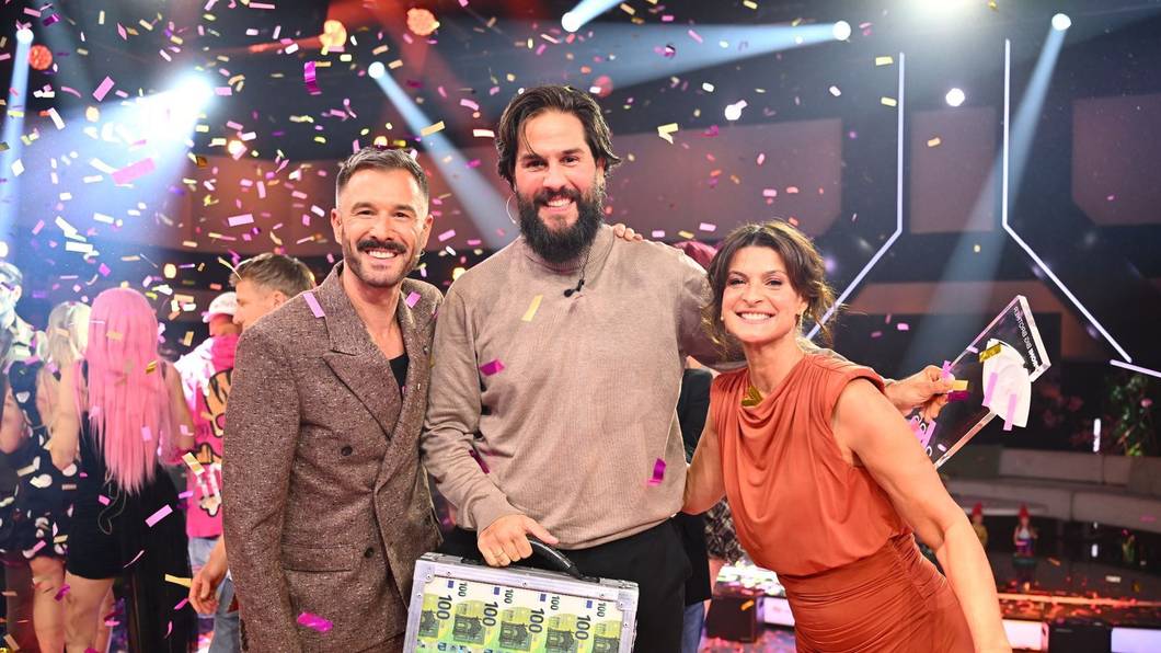 Maurice Dziwak (Mitte) bekommt von Jochen Schropp und Marlene Lufen den Pokal und 100.000 Euro überreicht. (Bild: Joyn/Willi Weber)