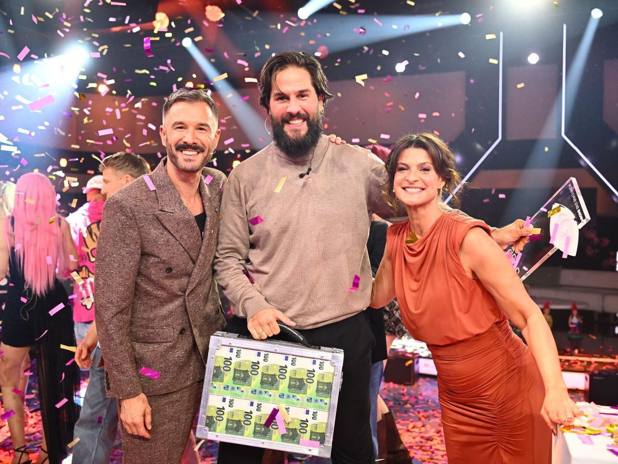 Maurice Dziwak (Mitte) bekommt von Jochen Schropp und Marlene Lufen den Pokal und 100.000 Euro überreicht. (Bild: Joyn/Willi Weber)