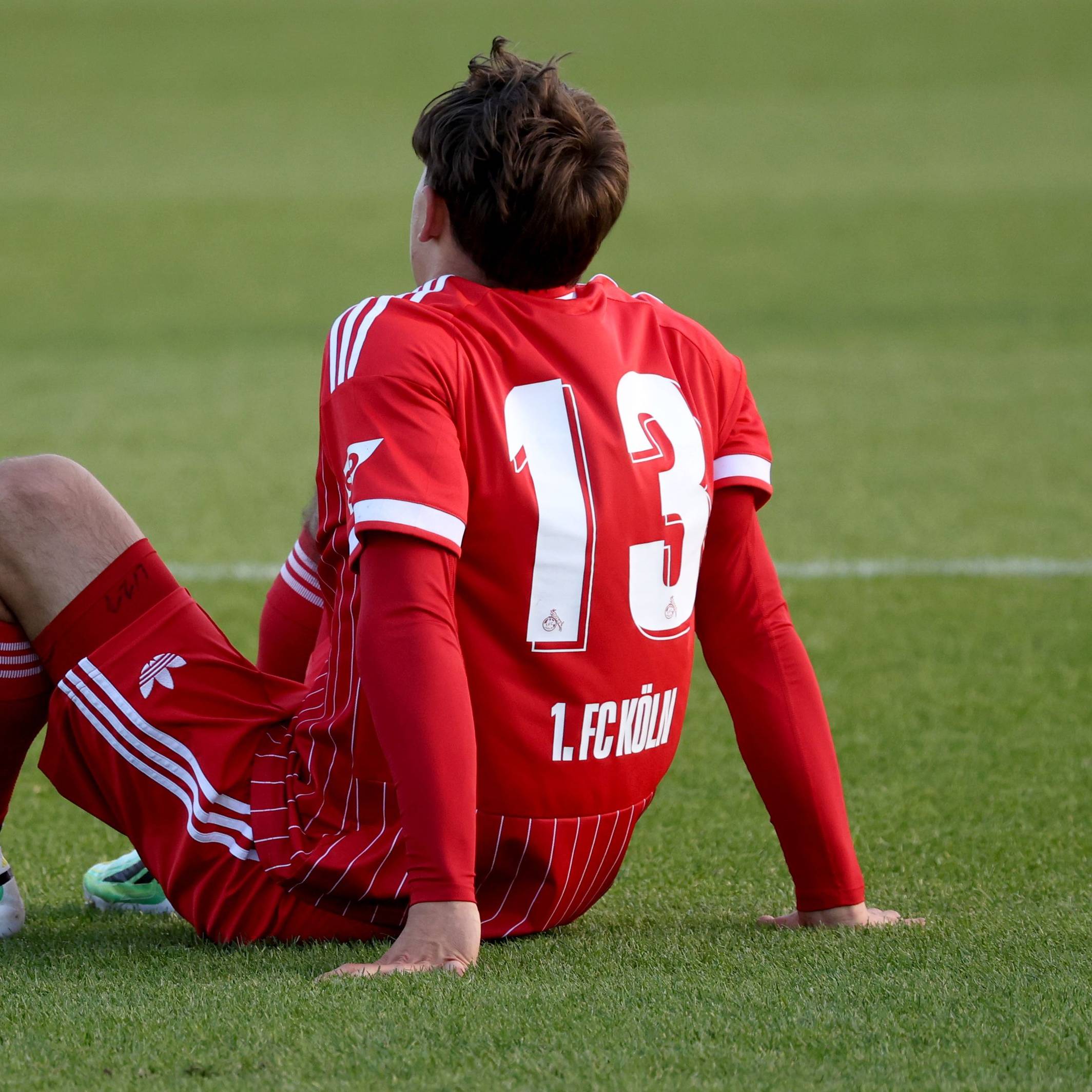 Cenny Neumann s (13) von Köln beim U23 Fußball Regionalliga-West Spiel zwischen FC Schalke 04 und dem 1.FC Köln sitzt verletzt auf dem Rasen.