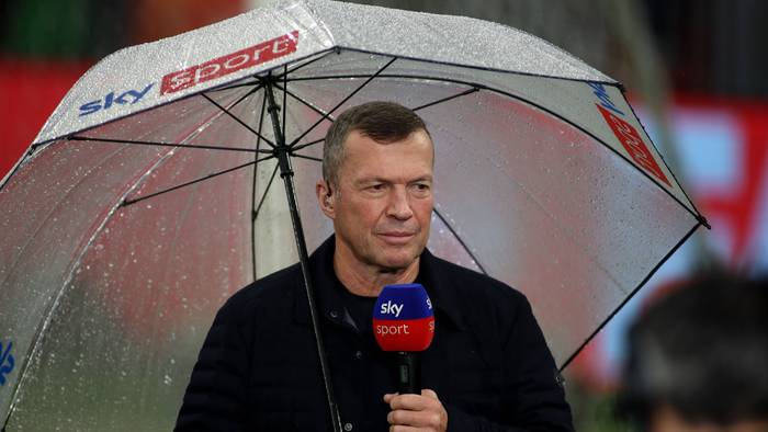 Lothar Matthäus mit Regenschirm und Sky-Mikro im Stadion.