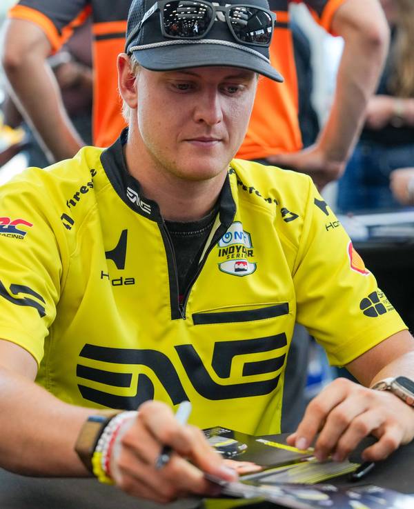 Mick Schumacher schreibt Autogrammt.