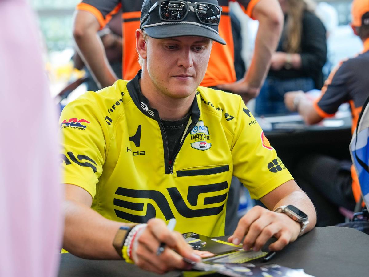 Mick Schumacher schreibt Autogrammt.