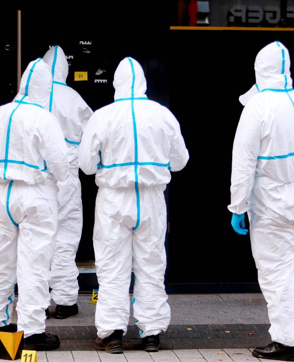 Vier Kräfte der Spurensicherung sind in Schutzanzügen vor dem Uhrengeschäft im Einsatz.