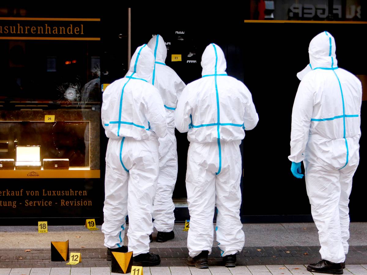 Vier Kräfte der Spurensicherung sind in Schutzanzügen vor dem Uhrengeschäft im Einsatz.
