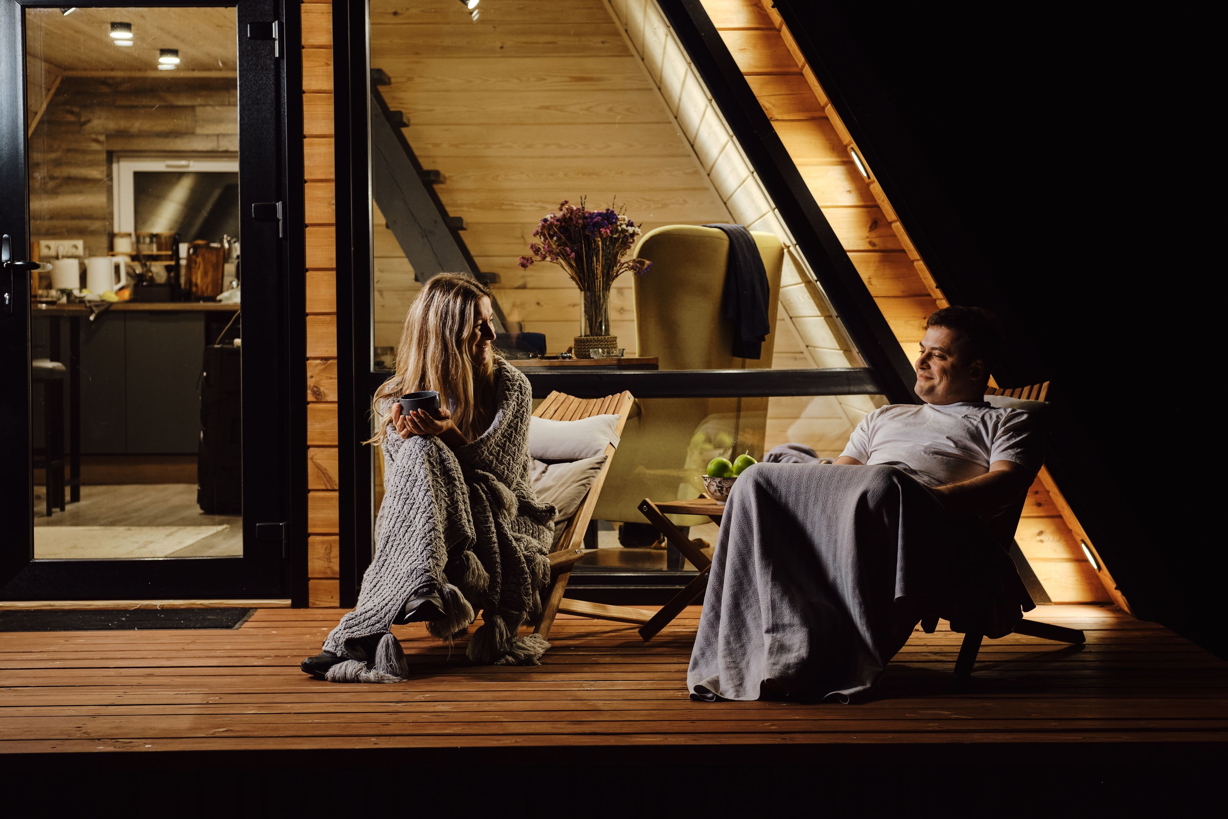 Pärchen hat es sich im Herbst vor einer Hütte gemütlich gemacht und in Decken gekuschelt