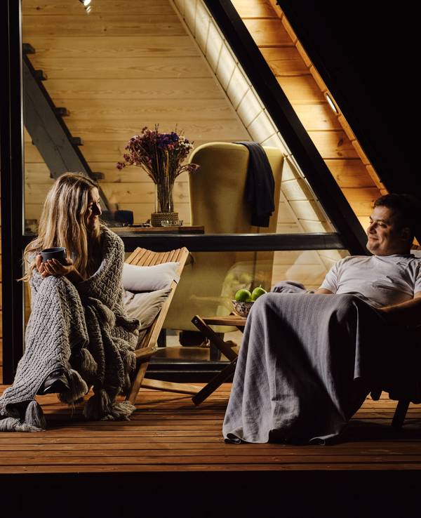 Pärchen hat es sich im Herbst vor einer Hütte gemütlich gemacht und in Decken gekuschelt