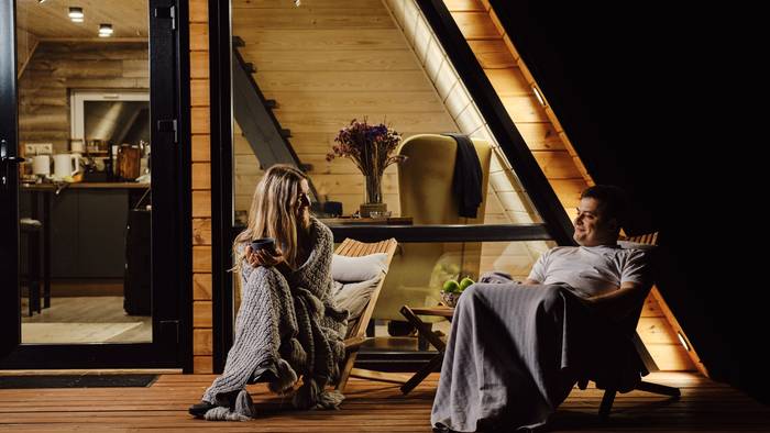 Pärchen hat es sich im Herbst vor einer Hütte gemütlich gemacht und in Decken gekuschelt