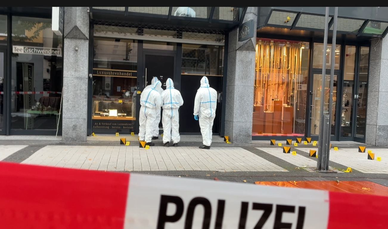 Ermittler stehen vor einem Uhrengeschäft.