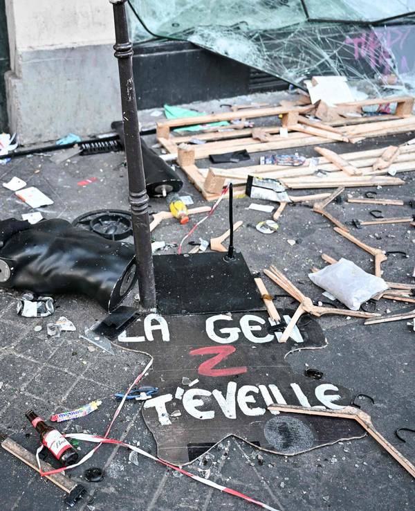 Ein Protestschild, eine zerstörte Schaufensterpuppe und Kleiderbügel liegen verstreut auf dem Boden.