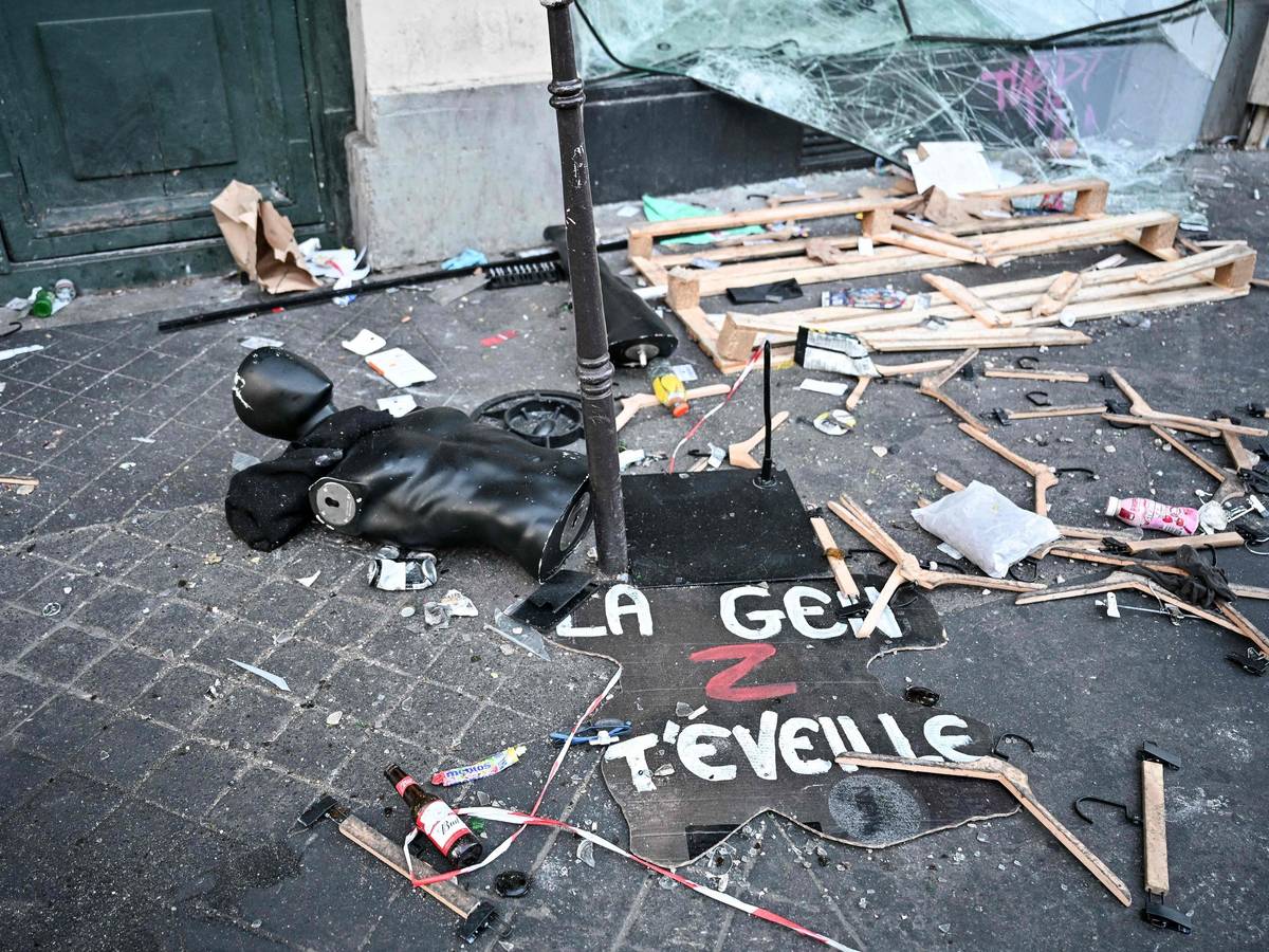 Ein Protestschild, eine zerstörte Schaufensterpuppe und Kleiderbügel liegen verstreut auf dem Boden.