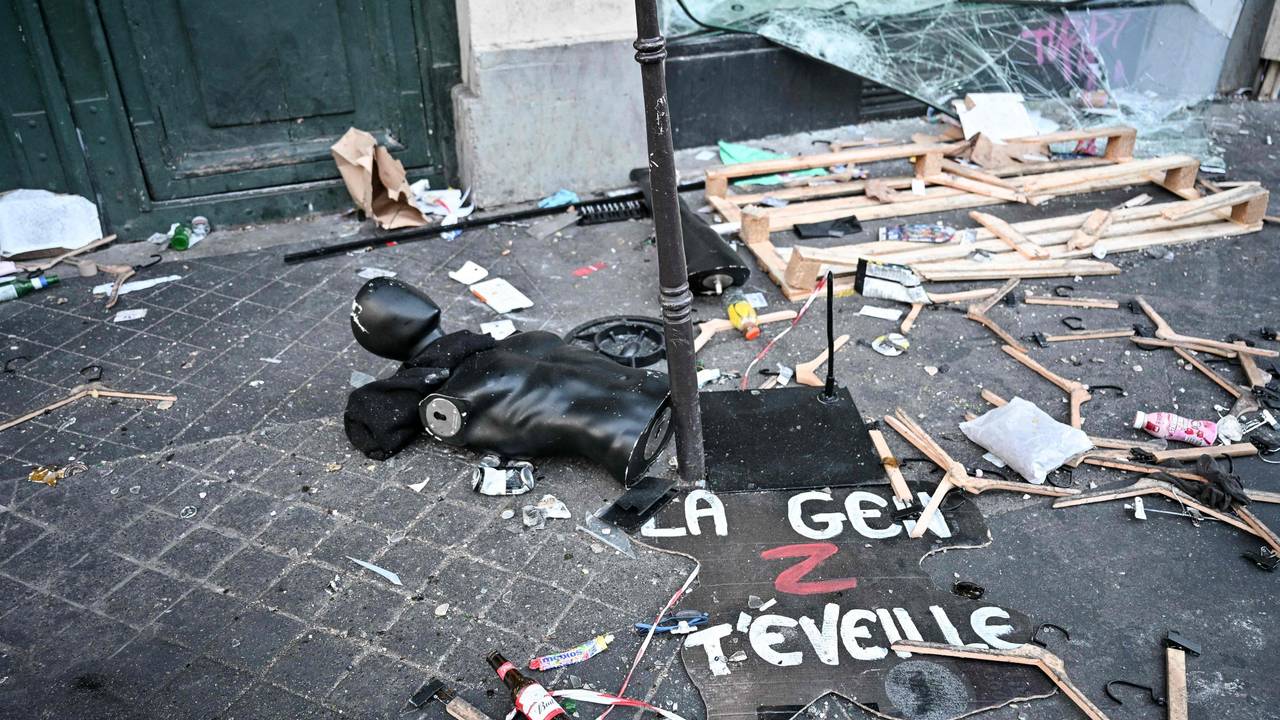 Ein Protestschild, eine zerstörte Schaufensterpuppe und Kleiderbügel liegen verstreut auf dem Boden.