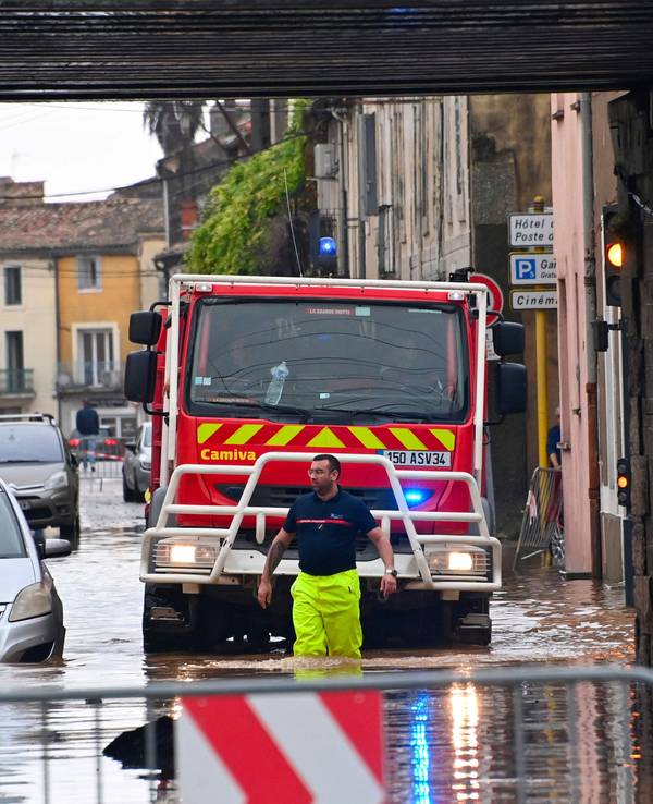 Ein Feuerwehrmann geht nach starken Regenfällen durch eine überflutete Straße in Lunel bei Montpellier in Südfrankreich.