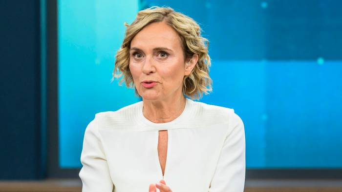 Caren Miosga spricht an einem Tisch.