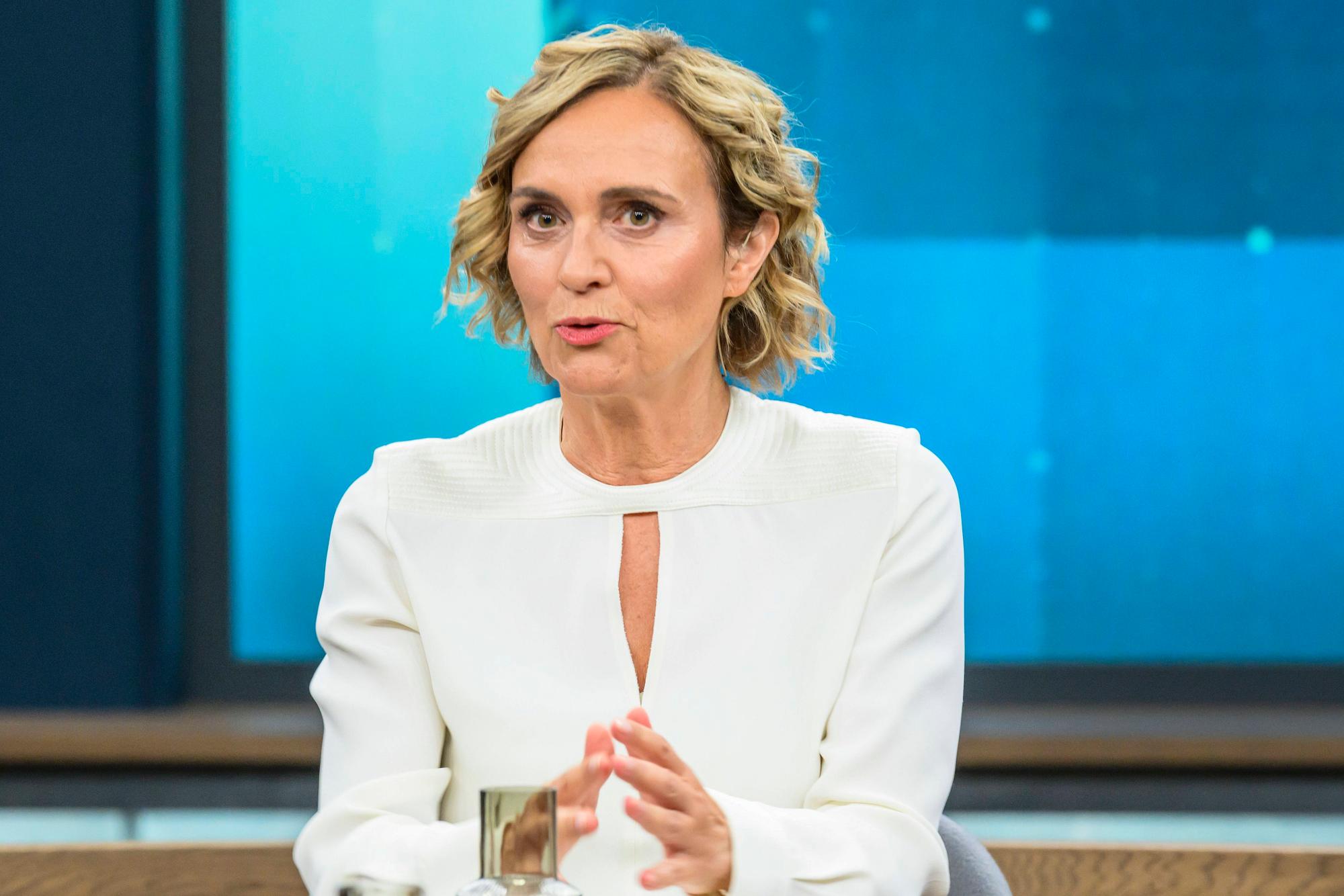 Caren Miosga spricht an einem Tisch.