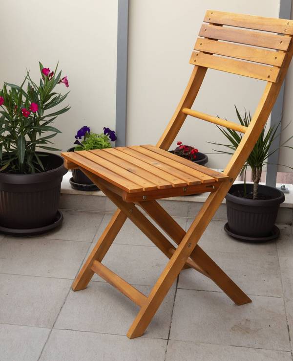 Holzstuhl und Topfpflanzen auf einem Balkon