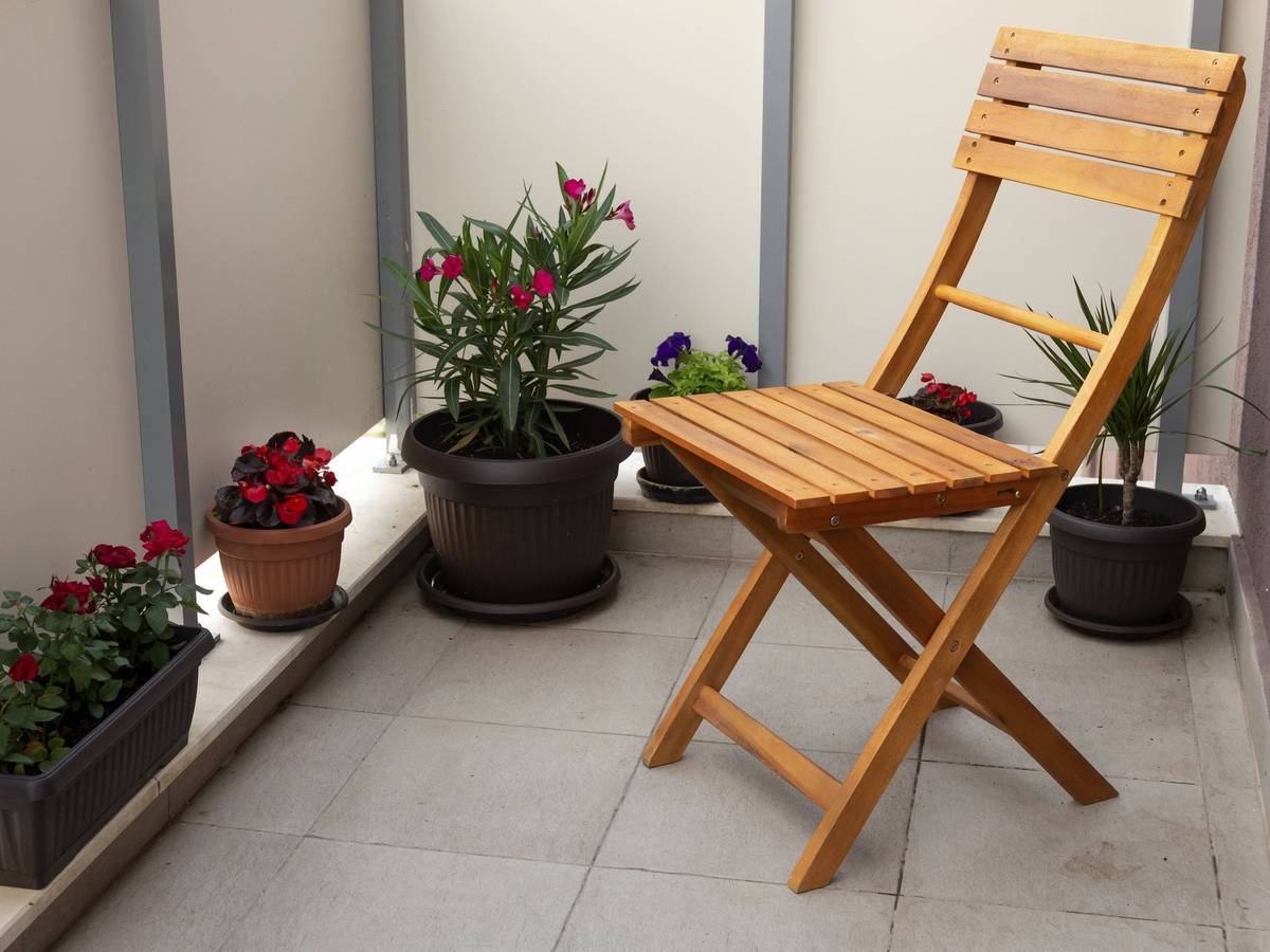 Holzstuhl und Topfpflanzen auf einem Balkon