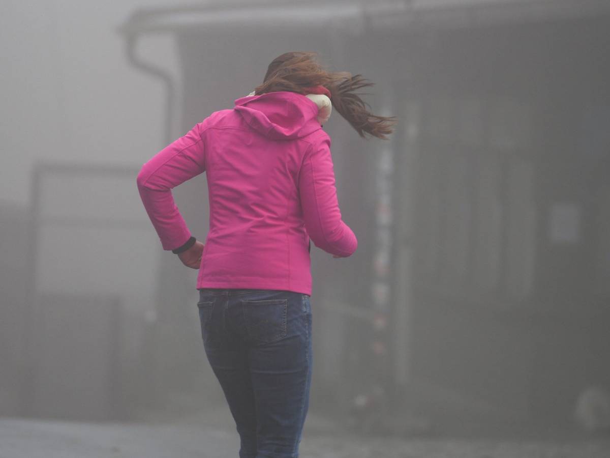 Frau kämpft auf dem Großen Feldberg im Taunus gegen Wind an