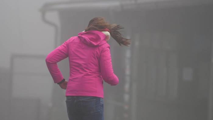 Frau kämpft auf dem Großen Feldberg im Taunus gegen Wind an