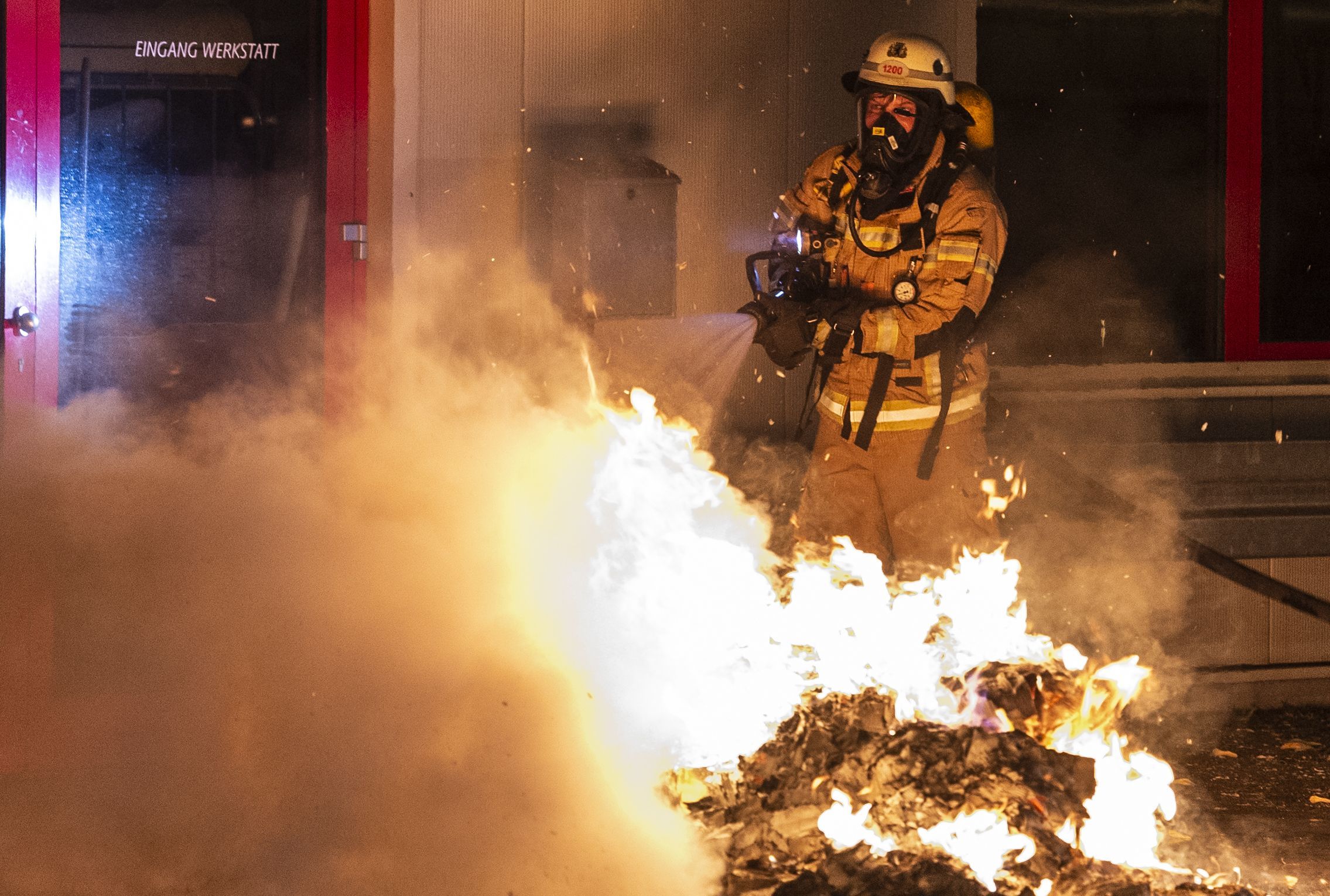 Ein Feuerwehrmann löscht eine Mülltonne.