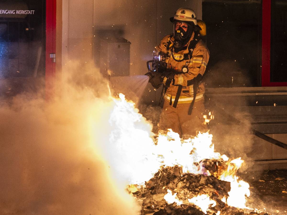 Ein Feuerwehrmann löscht eine Mülltonne.