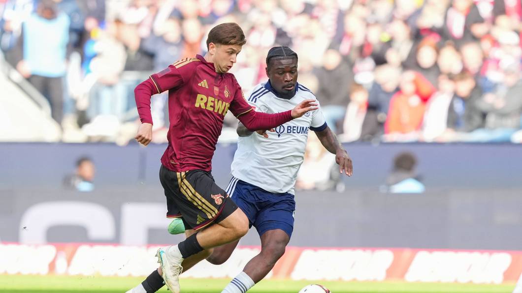 Mikey Moore (1. FC Köln) im Zweikampf gegen Junior Dina Ebimbe (FC Schalke 04).