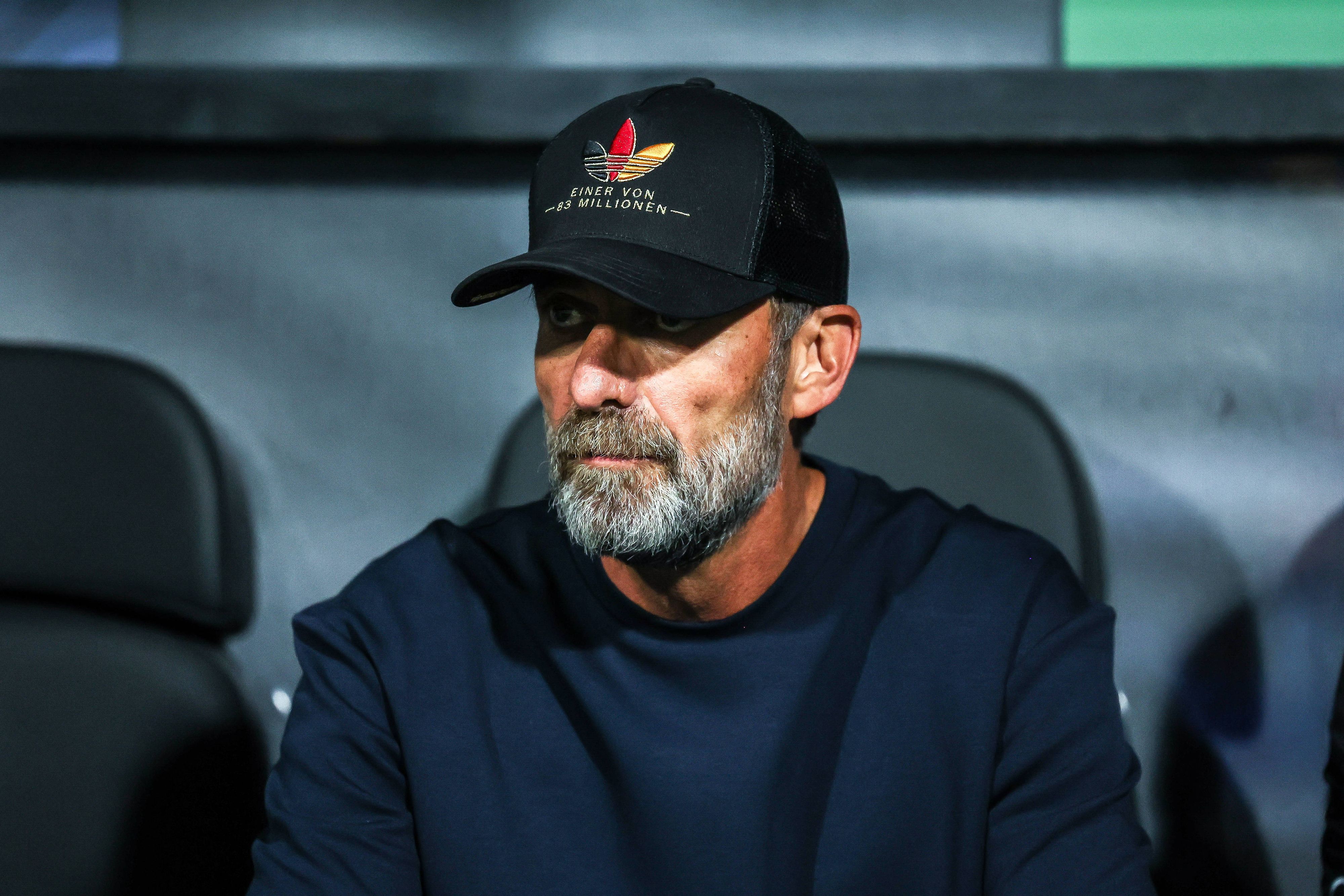 Jürgen Klopp trägt eine Kappe und sitzt auf der Trainerbank.