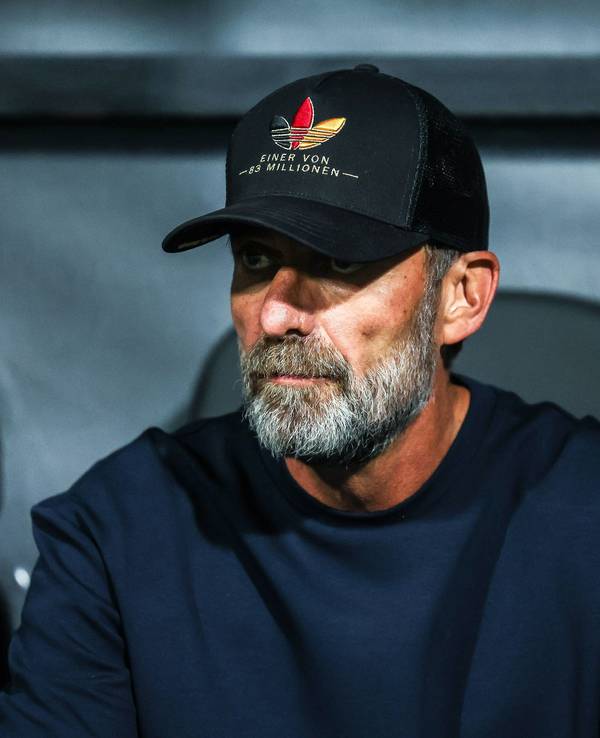 Jürgen Klopp trägt eine Kappe und sitzt auf der Trainerbank.