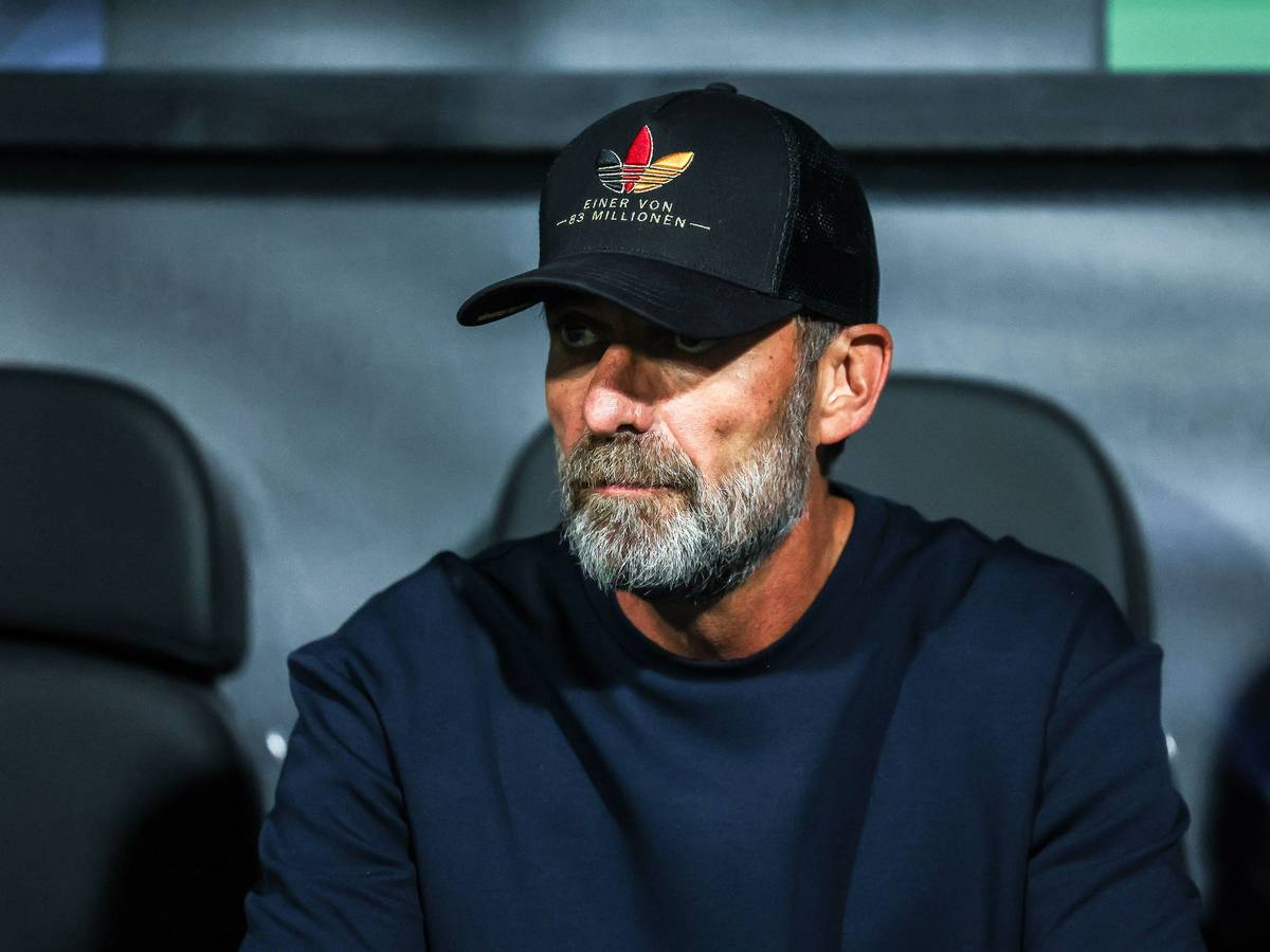 Jürgen Klopp trägt eine Kappe und sitzt auf der Trainerbank.