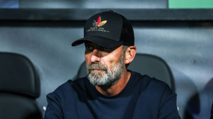 Jürgen Klopp trägt eine Kappe und sitzt auf der Trainerbank.