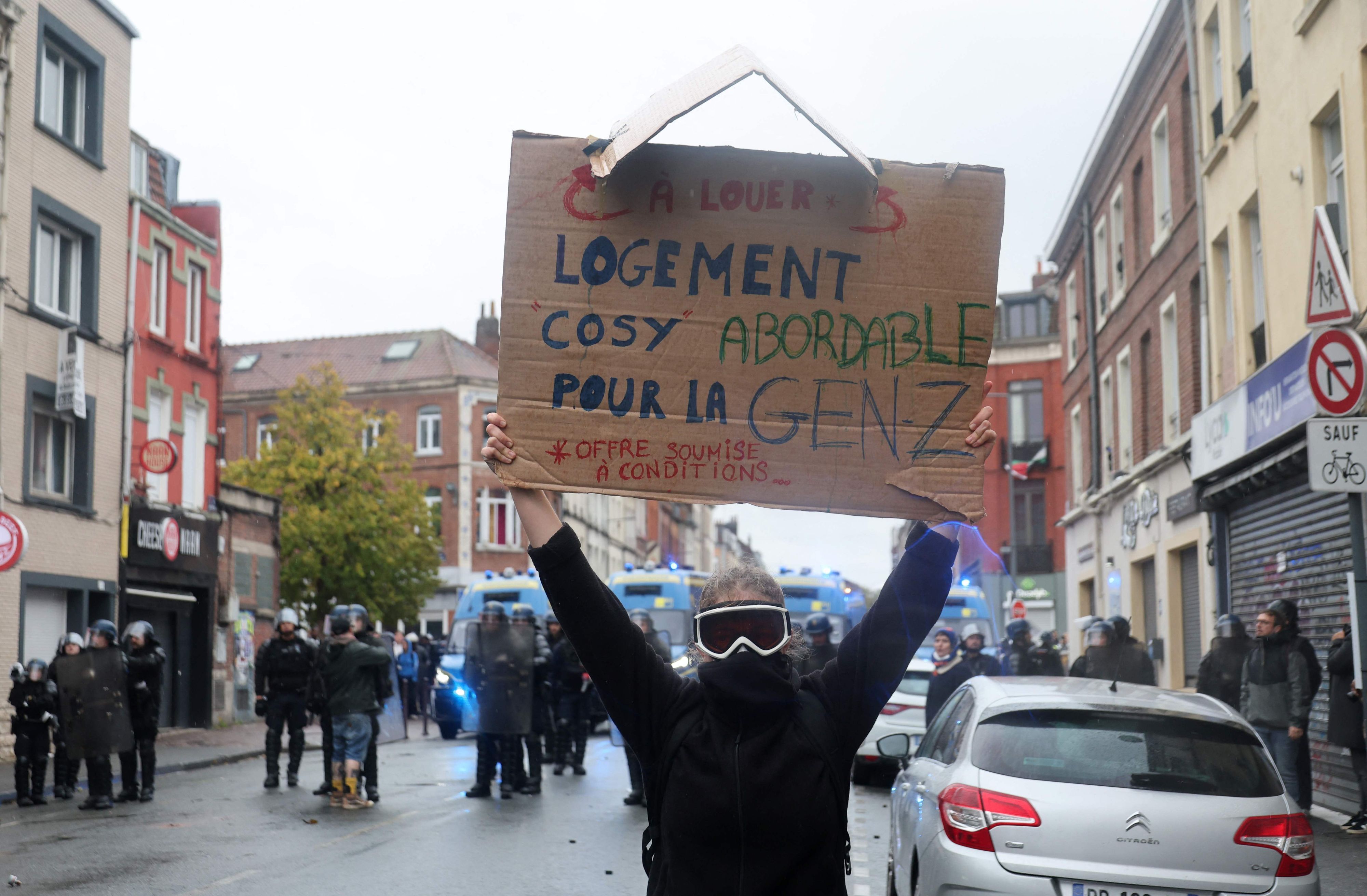 Ein vermummter Aktivist bei einer Demo in Frankreich. Er hält ein „Gen Z“-Schild in die Luft.