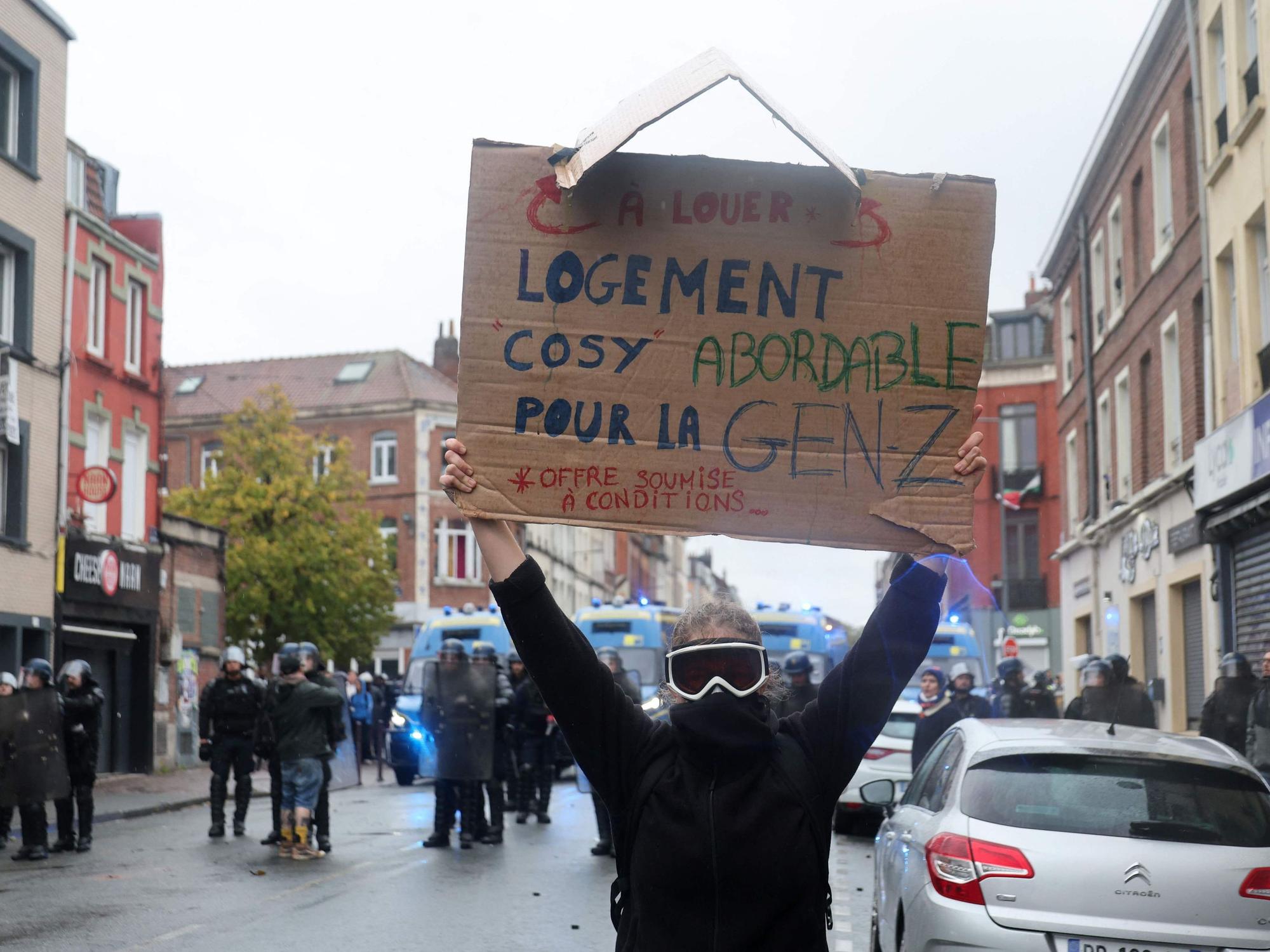 Ein vermummter Aktivist bei einer Demo in Frankreich. Er hält ein „Gen Z“-Schild in die Luft.