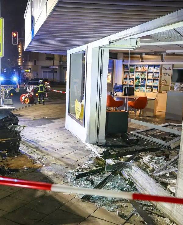 Hinter Absperrband steht ein demoliertes Auto vor einer kaputten Schaufensterscheibe. Ein Autofahrer ist am Samstagabend aus bislang ungeklärten Gründen mit seinem Wagen in ein Reisebüro gefahren.