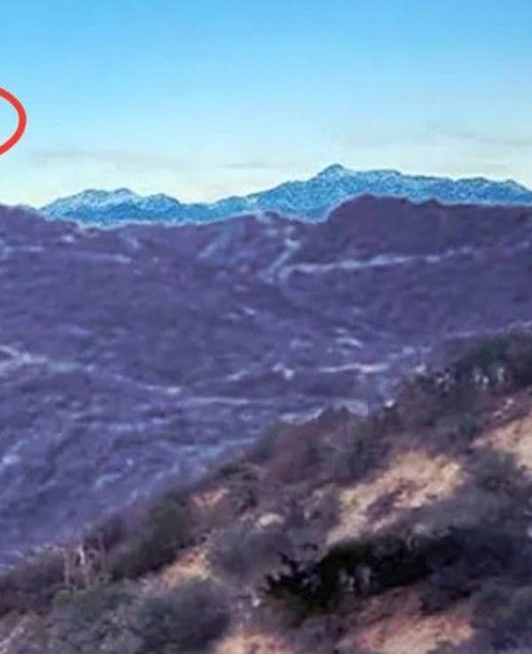 Ein Bild, das zusammen mit einem FBI-Bericht aus dem Jahr 2026 veröffentlicht wurde, zeigt ein schwarzes, dreieckiges Objekt über bergigem Gelände.