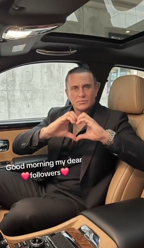 Neco Arabaci sitzt in einem Luxusauto und grüßt seine Follower.
